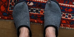Eine Person steht mit Pantoffeln auf einem Teppich