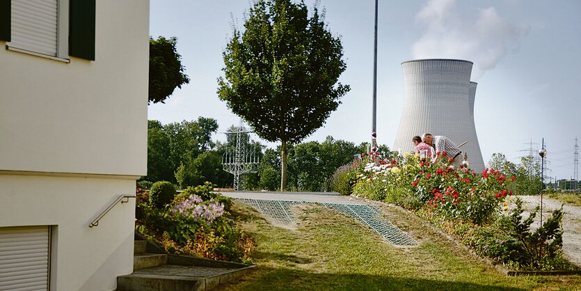 Ein Paar bei der Gartenarbeit. Im Hintergrund sind die Kühltürme des AKW Gundremmingen zu sehen.