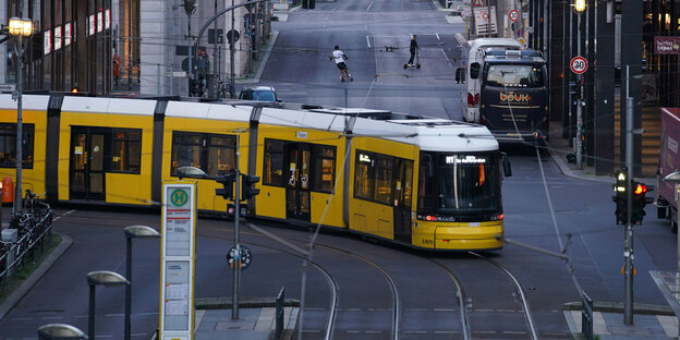Eine Straßenbahn biegt in Berlin-Mitte um die Ecke. Im Hintergrund zwei Personen auf E-Scootern
