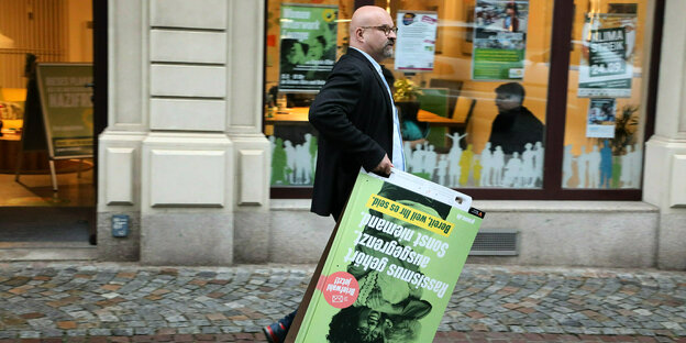 Ein Mann trägt ein Wahlplakat der Grünen durch die Stadt