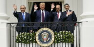 Vier Politiker stehen auf einem Balkon und winken