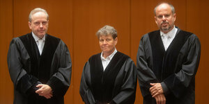 Zwei Männer und eine Frau (Staatsanwälte) stehen in ihren Roben vor der Kamera