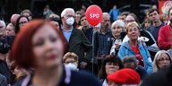 Menschen stehen auf einem Platz und hören zu, in der Mitte ein roter Luftballon mit der Aufschrift SPD