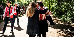 Ein küssenden Paar in Unionklamotten auf dem Weg durch den Wald zum Stadion