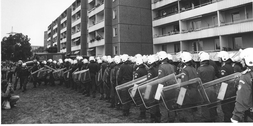 Eine bewaffnete Polizeikette steht vor einem Hochhaus in Hoyerswerda