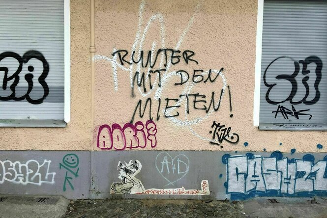 Auf einer Hauswand ist ein Graffiti "Runter mit den Mieten"