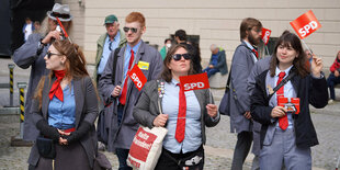 Menschen mit schlecht sitzenden Anzügen wedeln mit Fahnen