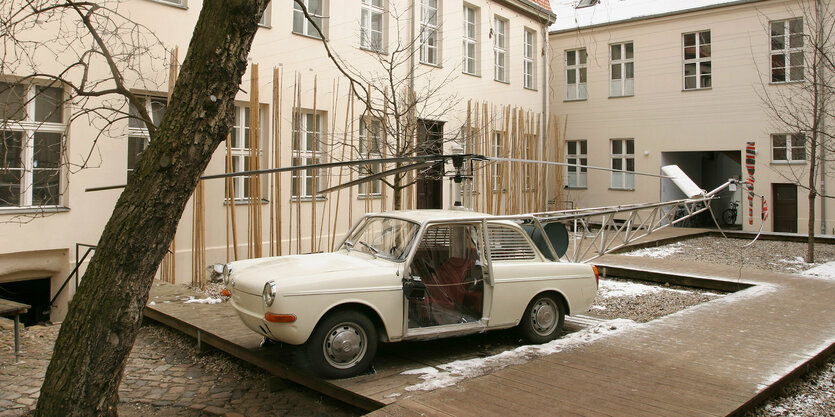 Im Hof der Kunst-Werke sieht man ein älteres Auto mit Hubschrauberanteilen stehen