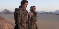 Paul Atreides (Timothée Chalamet) und Lady Jessica (Rebecca Ferguson) stehen auf Arrakis im Wüstensand.