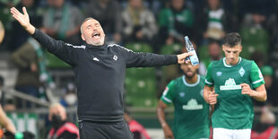 HSV-Trainer Tim Walter jubelt mit ausgebreiteten Armen und Wasserflasche in der Hand. Im Hintergrund Bremer Spieler