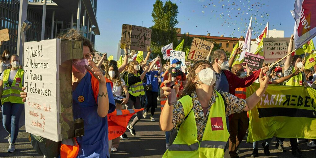 Demonstrierende mit Schildern und VERDI Fahnen ziehen durch die Straße