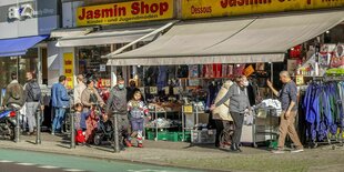 Menschen laufen an einer EInkaufsstraße mit vielen kleinen Läden vorbei