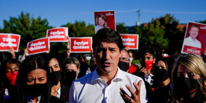 Justin Trudeau spricht mit erhobener Hand, vor Anhängern stehend