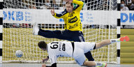 Ein Handballspieler wirft quer in der Luft liegend ins Tor