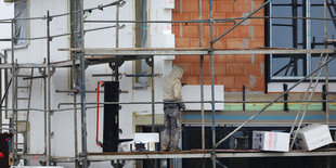 Ein Handwerker bringt Dämmmaterial an einen Neubau an