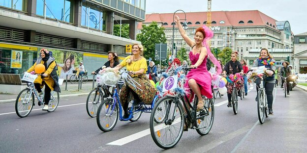 Frauen, bunt gekleidet, radeln durch die Straßen von Berlin