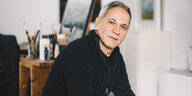 Der Künstler und Sozialarbeiter Majid Tabe sitzt in seinem Atelier im hannoverschen Stadtteil Ahlem vor einer Staffelei mit Malutensilien.