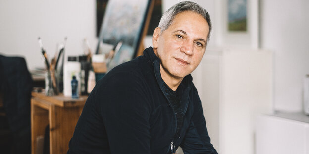 Der Künstler und Sozialarbeiter Majid Tabe sitzt in seinem Atelier im hannoverschen Stadtteil Ahlem vor einer Staffelei mit Malutensilien. Der Künstler und Sozialarbeiter Majid Tabe sitzt in seinem Atelier im hannoverschen Stadtteil Ahlem vor einer Staffelei mit Malutensilien.