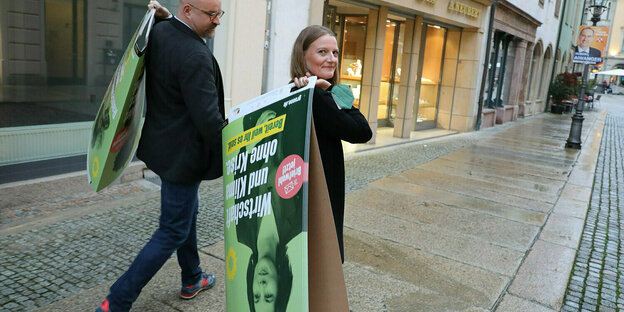 Ein mann und eine Frau mit Wahlplakaten der Grünen