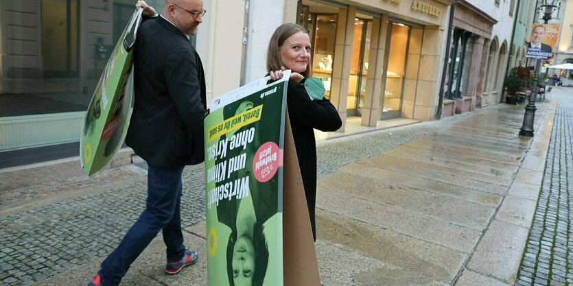 Ein mann und eine Frau mit Wahlplakaten der Grünen