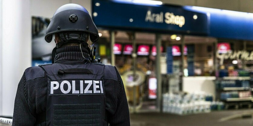 Ein Polizist steht vor der Tankstelle, in der ein 20-jähriger Verkäufer erschossen wurde, nachdem er auf die Maskenpflicht hinwies