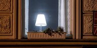 Eine Lampe leuchtet in einem nächtlichen Fenster