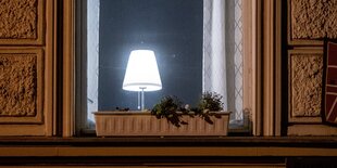 Eine Lampe leuchtet in einem nächtlichen Fenster