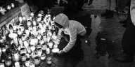 Ein Kind stellt eine Gedenkkerze in ein Kerzenmeer