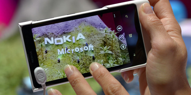 EinHandy-Display zeigt eine Wiese mit den Schriftzügen von Nokia und Microsoft
