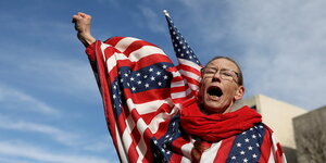 Eine Frau ist in eine US-Fahne gehüllt und schreit