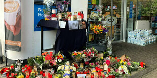 Blumen und Kerzen sind vor einer Tankstelle aufgestellt.