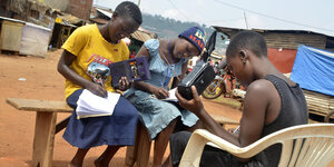 Jugendliche hören einem Radio zu und schreiben in ihre Hefte