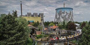 Ein Freizeitpark, im Hintergrund die Bauruine eines Atomreaktors, der mit einem Landschaftspanoroma bemalt ist