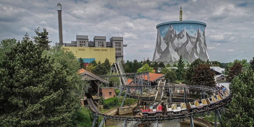 Ein Freizeitpark, im Hintergrund die Bauruine eines Atomreaktors, der mit einem Landschaftspanoroma bemalt ist