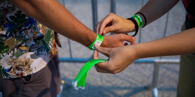 Einem Mann wird ein grünes Band am Handgelenk befestigt