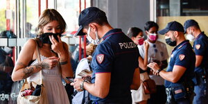 Drei Polizisten stehen kontrollieren das Smartphone von jungen Leuten