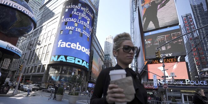 Eine Frau geht an Leuchtreklametafeln am Times Square in new York vorbei