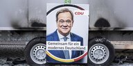 Ein Wahlplkat der CDU mit dem Foto von Armin Laschet ist an ein Auto gelehnt