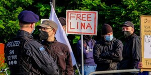 Eine Menschengruppe und ein Polizist, auf einem Plakat steht "Free Lina"