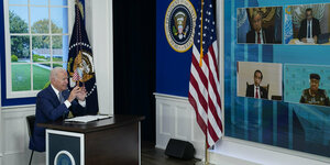 US-Präsident Joe Biden sitzt an einem Pult vor einer Videowand mit Konferenzteilnehmern