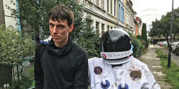 Zwei Menschen gehen auf einer Bremer Straße. Einer trägt einen Astronautenanzug.
