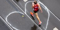 Ein Teilnehmer des Berlin-Marathons läuft über ein auf der Straße aufgemaltes Herz