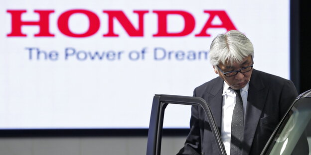 Ein Mann steigt in ein Auto ein, im Hintergrund der Schriftzug "Honda - The Power of Dreams"