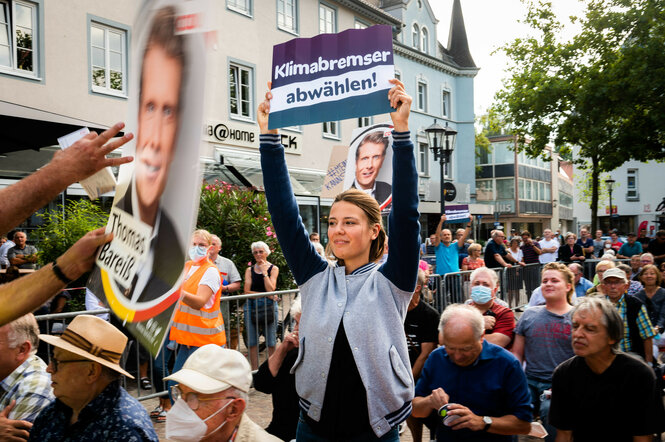 Eine Frau in einer Menschenmenge hält ein Plakat mit dem Slogan "Klimabremser abwählen!"