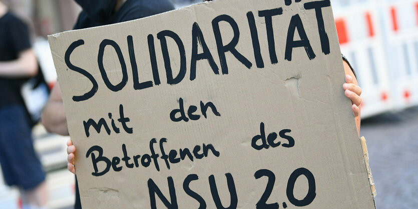 Frau mit Solidaritätsaufruf-Plakat.