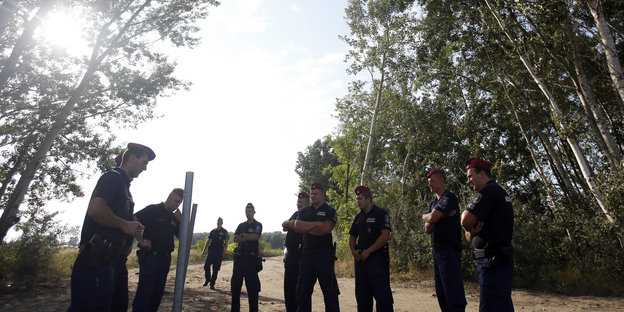 Ungarische Polizisten bewachen den Beginn der Arbeiten des Grenzzauns.
