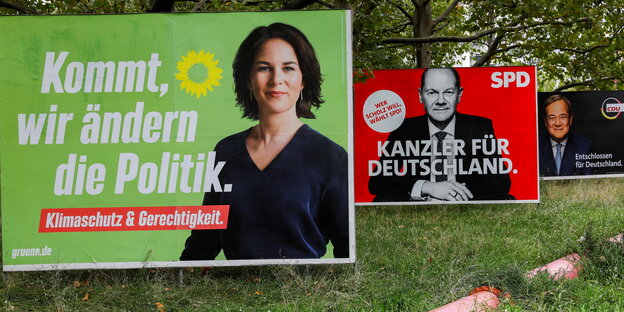 Ein Wahlplakat, das Annalena Baerbock zeigt, dahinter eines von Scholz, dahinter Laschet