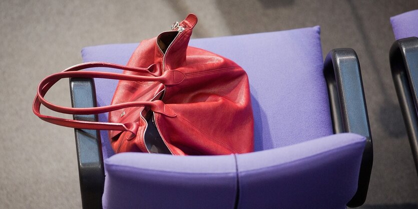 Die rote Handtasche von Angela Merkel liegt auf einem Sitz im Bundestag