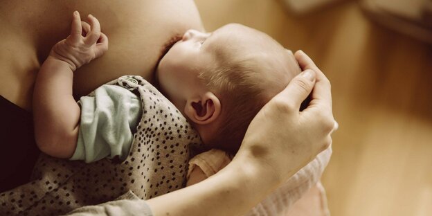 Ein Neugeborenes saugt an einer Brust