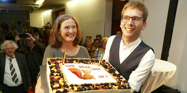 Elke Kahr und Stadtrat Robert Krotzer tragen eine große Torte